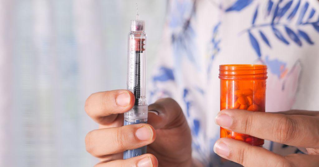 Close up of a person holding a GLP pen in one hand and a pill bottle in the other.