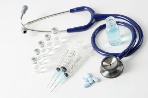 An over-head shot of a stethoscope, pills, injectable weight loss medications laying on a table.
